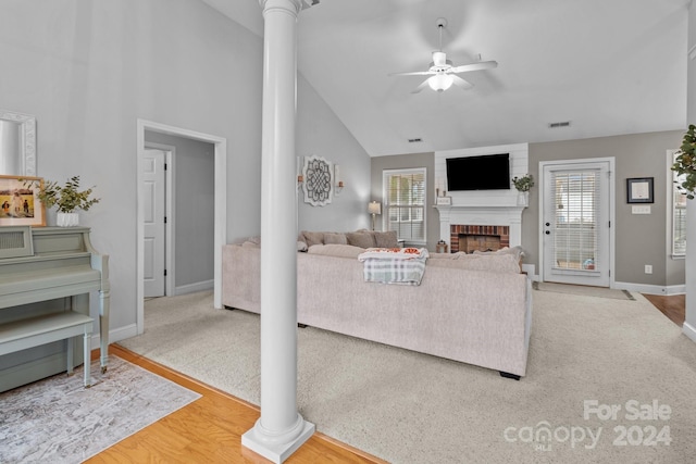 living room with a brick fireplace, hardwood / wood-style flooring, ceiling fan, and ornate columns