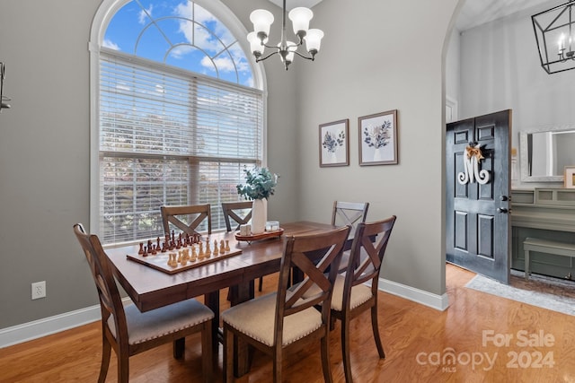 dining space with light hardwood / wood-style flooring, a high ceiling, and an inviting chandelier