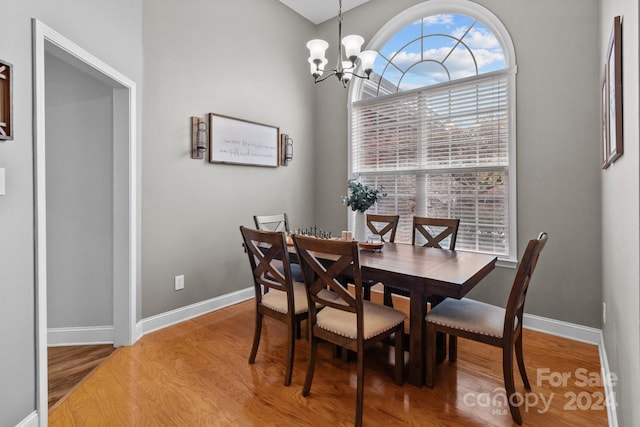 dining room with hardwood / wood-style floors, plenty of natural light, and an inviting chandelier