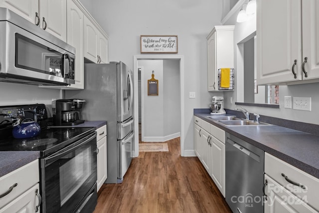 kitchen with dark hardwood / wood-style floors, white cabinetry, sink, and appliances with stainless steel finishes