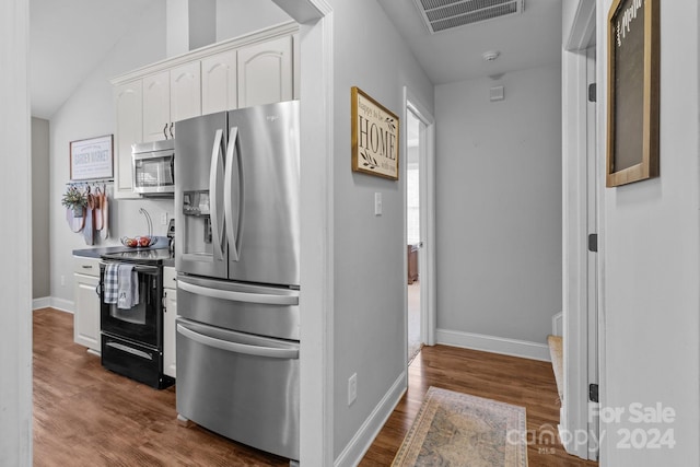 kitchen featuring white cabinets, stainless steel appliances, lofted ceiling, and hardwood / wood-style flooring