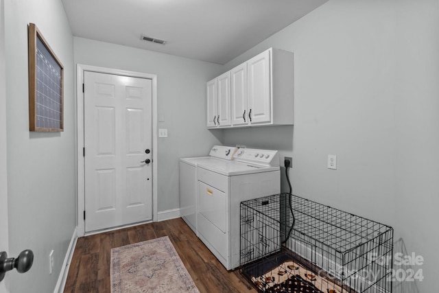 clothes washing area with dark hardwood / wood-style flooring, washing machine and dryer, and cabinets