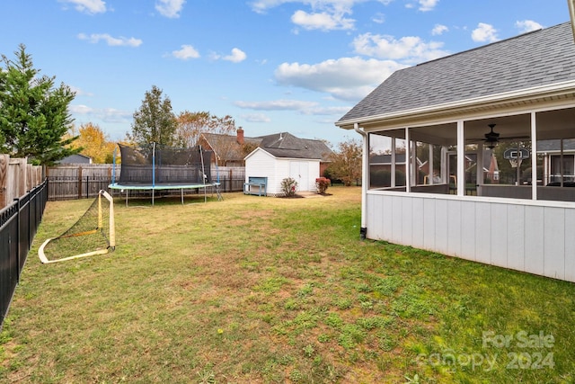 view of yard with a sunroom, a shed, a trampoline, and ceiling fan