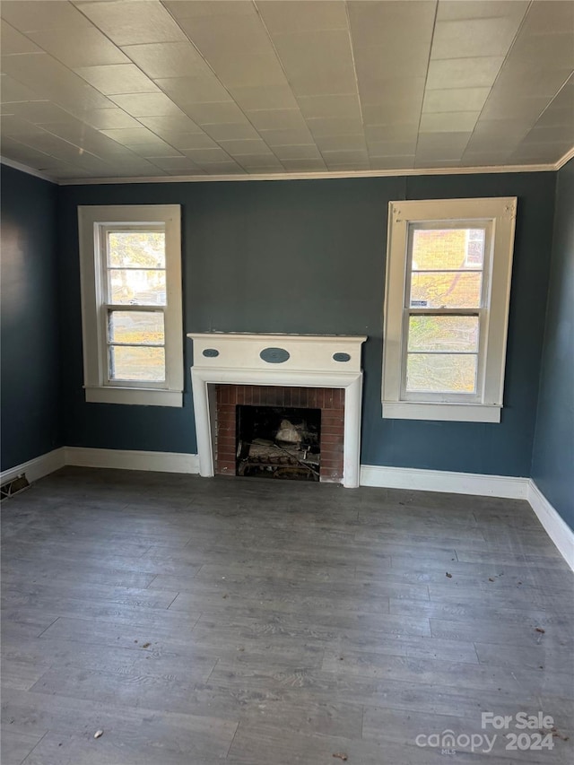 unfurnished living room featuring crown molding, wood-type flooring, and a brick fireplace