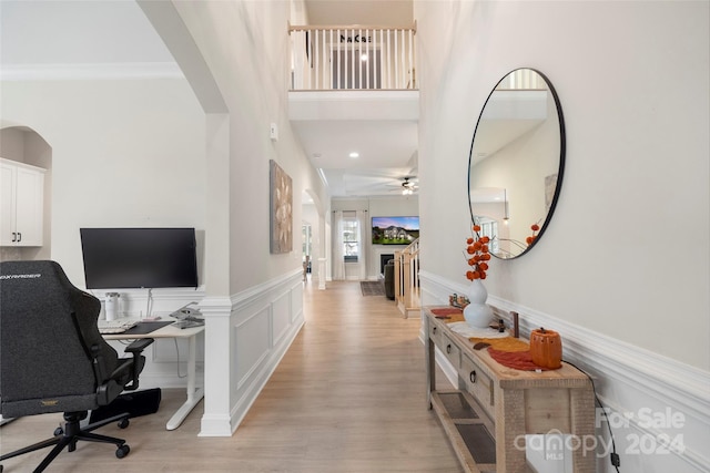 entryway with ceiling fan, a towering ceiling, and light hardwood / wood-style flooring