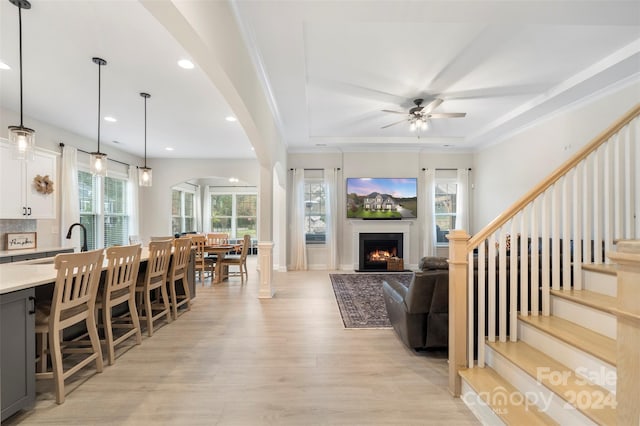 living room featuring ornamental molding, sink, light hardwood / wood-style flooring, and ceiling fan