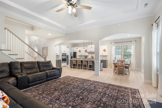 living room with crown molding, light hardwood / wood-style flooring, a raised ceiling, and ceiling fan