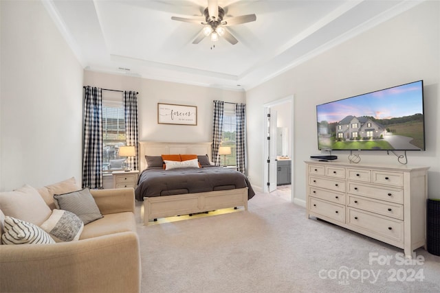 carpeted bedroom with connected bathroom, a raised ceiling, multiple windows, and ceiling fan