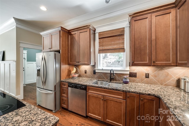 kitchen featuring appliances with stainless steel finishes, sink, light stone counters, and light hardwood / wood-style floors