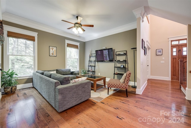 living room featuring crown molding, wood-type flooring, and a healthy amount of sunlight