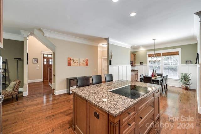 kitchen with a chandelier, black electric cooktop, dark wood-type flooring, pendant lighting, and a center island