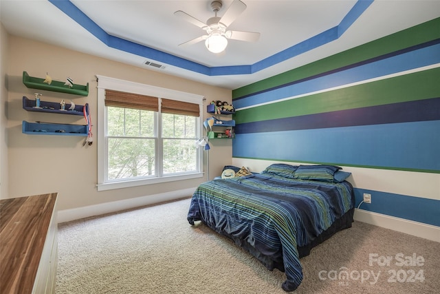 carpeted bedroom with a tray ceiling and ceiling fan