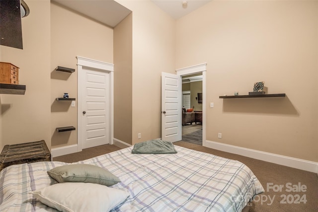 bedroom with dark carpet and a towering ceiling