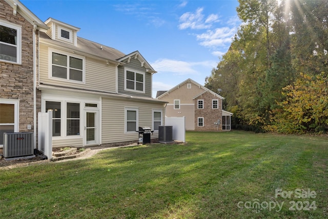 back of house with central AC and a yard