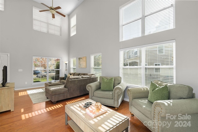 living room featuring ceiling fan, hardwood / wood-style flooring, and a high ceiling