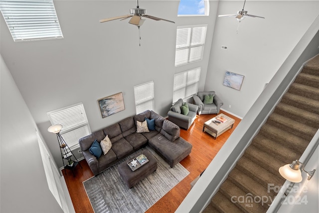 living room with hardwood / wood-style floors, a towering ceiling, and ceiling fan