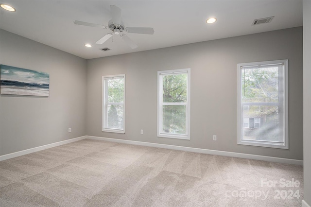 carpeted spare room featuring a healthy amount of sunlight and ceiling fan