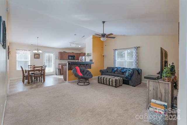 carpeted living room with rail lighting, vaulted ceiling, and ceiling fan with notable chandelier