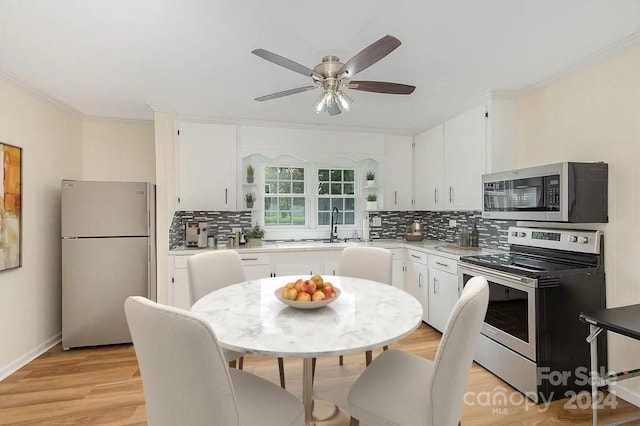 kitchen with appliances with stainless steel finishes, light hardwood / wood-style flooring, white cabinetry, and backsplash