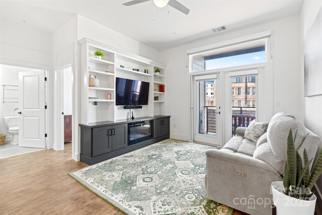 living area featuring a ceiling fan, visible vents, and light wood-style floors