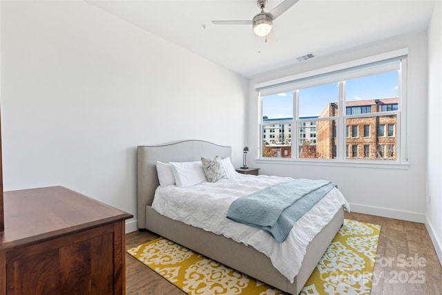 bedroom featuring a ceiling fan, baseboards, visible vents, and wood finished floors