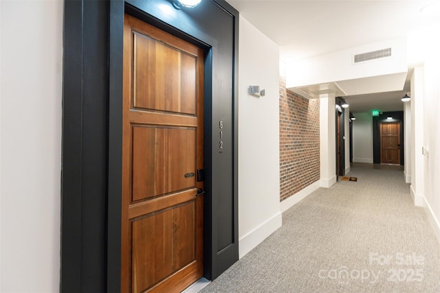 corridor featuring light carpet, brick wall, visible vents, and baseboards