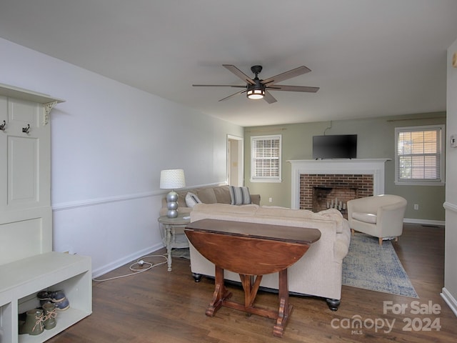 living room featuring dark hardwood / wood-style flooring, ceiling fan, and a brick fireplace