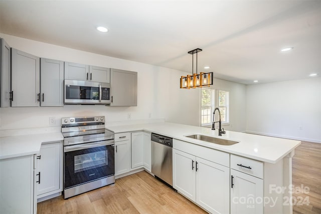 kitchen featuring kitchen peninsula, stainless steel appliances, sink, and light wood-type flooring