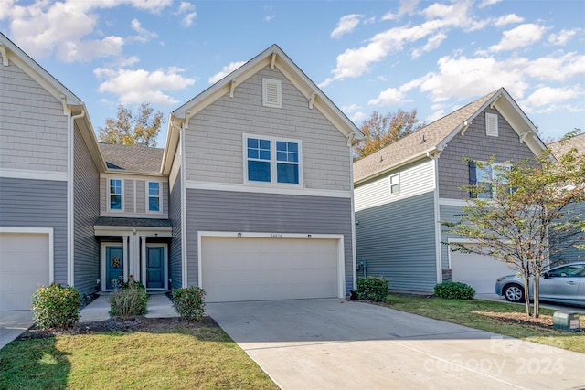 traditional-style house featuring an attached garage, a front lawn, and driveway