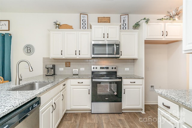 kitchen with white cabinets, light hardwood / wood-style floors, sink, and appliances with stainless steel finishes