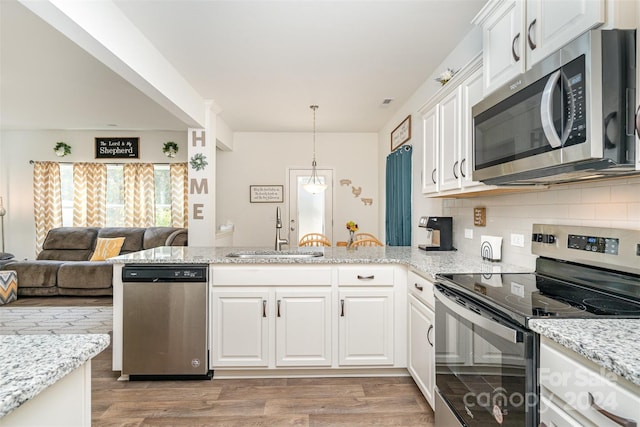 kitchen with a peninsula, light wood-style flooring, a sink, white cabinets, and appliances with stainless steel finishes