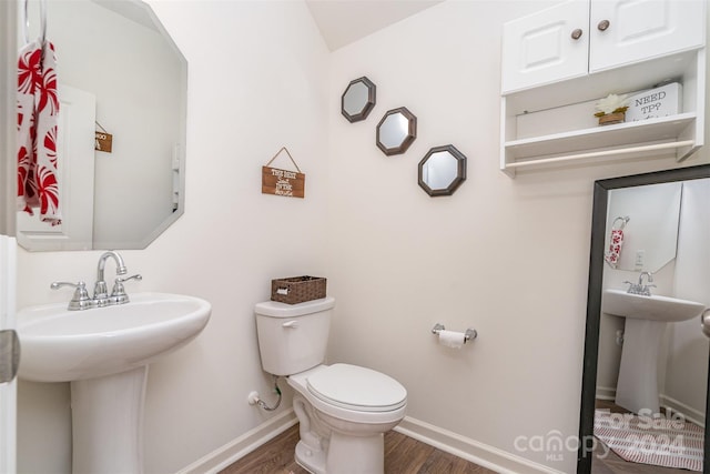 bathroom with a sink, toilet, baseboards, and wood finished floors