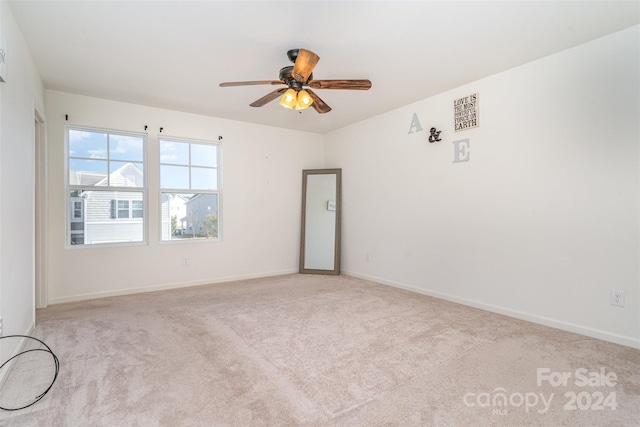 carpeted spare room with baseboards, visible vents, and ceiling fan