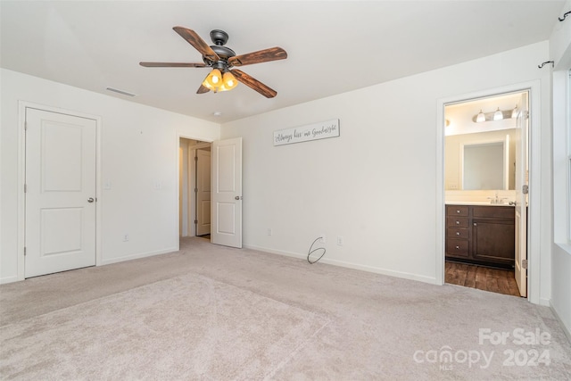 unfurnished bedroom featuring ceiling fan, ensuite bath, and light colored carpet