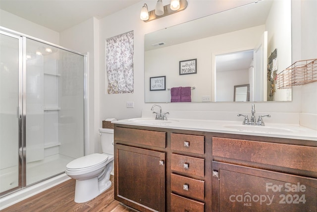 bathroom featuring hardwood / wood-style floors, a shower with door, vanity, and toilet