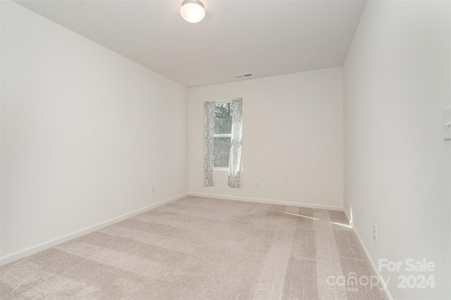 unfurnished room with light colored carpet, visible vents, and baseboards