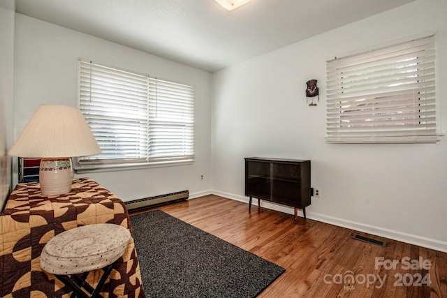 sitting room with a baseboard heating unit and hardwood / wood-style floors