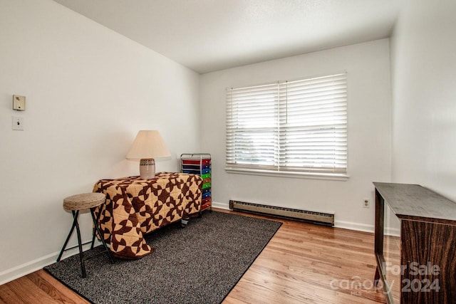 living area with a baseboard heating unit and hardwood / wood-style flooring