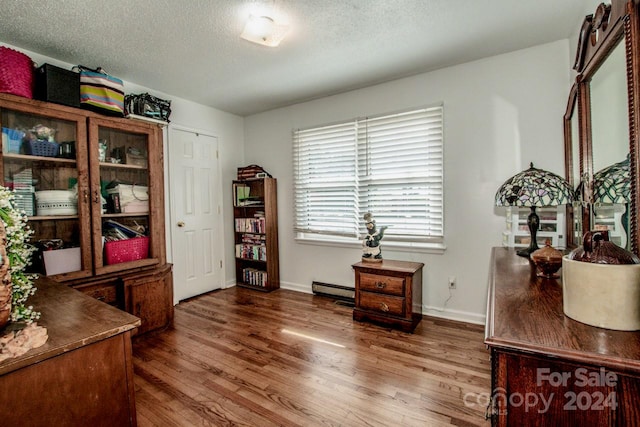 office featuring dark hardwood / wood-style floors, baseboard heating, and a textured ceiling