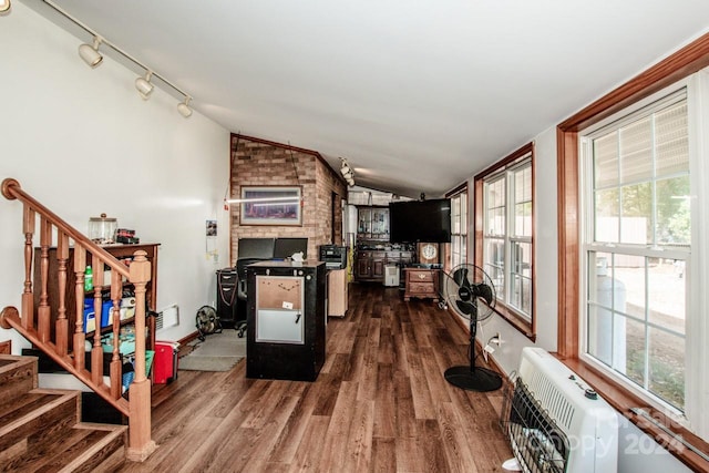 interior space featuring heating unit, track lighting, vaulted ceiling, and dark hardwood / wood-style floors