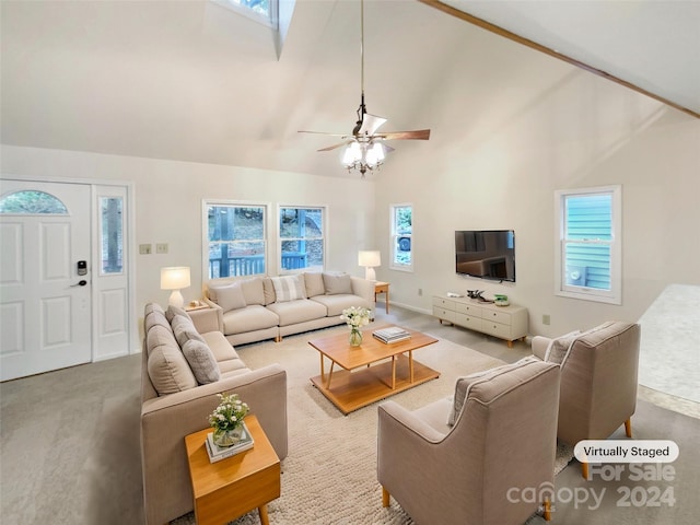 living room featuring high vaulted ceiling, a skylight, ceiling fan, and carpet floors