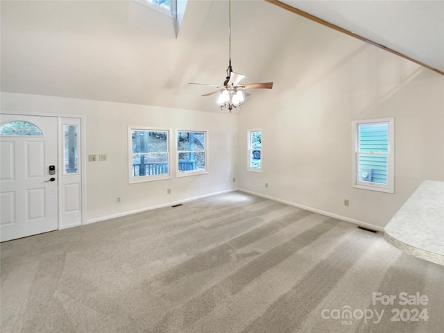 unfurnished living room featuring high vaulted ceiling, ceiling fan, a skylight, and carpet