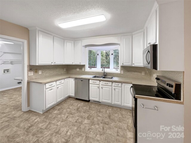 1259 Blacksnake Rd, Stanley, NC 28164 - kitchen featuring appliances with stainless steel finishes, a sink, white cabinets, a textured ceiling, and light countertops