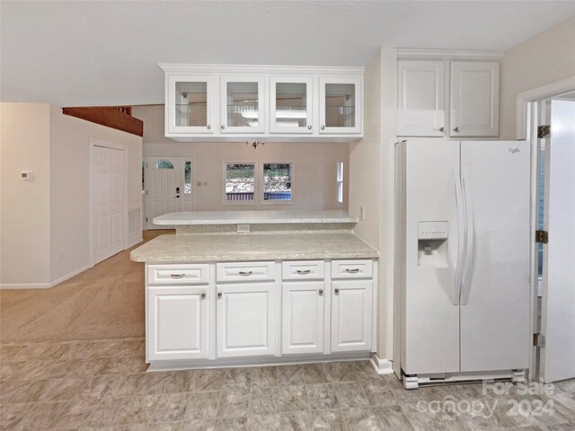 1259 Blacksnake Rd, Stanley, NC 28164 - kitchen with white refrigerator with ice dispenser, a peninsula, light countertops, white cabinetry, and glass insert cabinets