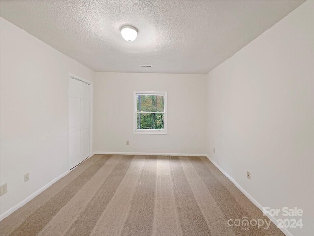 1259 Blacksnake Rd, Stanley, NC 28164 - empty room featuring a textured ceiling, carpet, and baseboards
