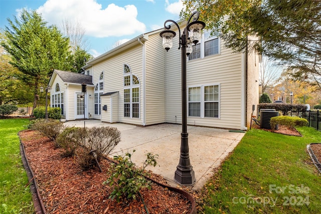 rear view of property featuring a yard, central AC unit, and a patio area