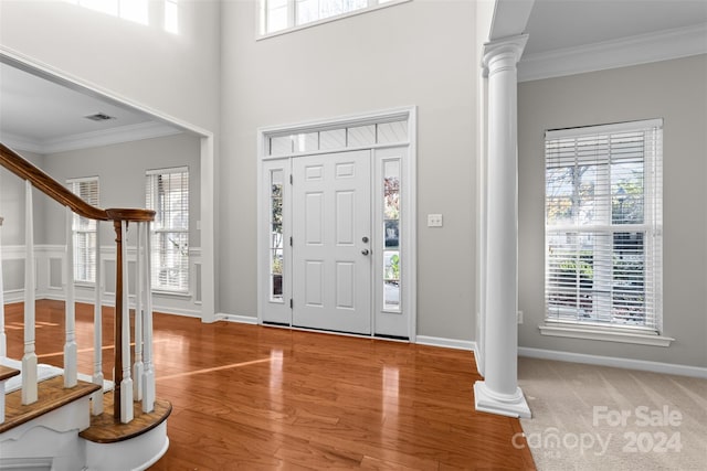 entrance foyer with hardwood / wood-style flooring, ornate columns, and crown molding