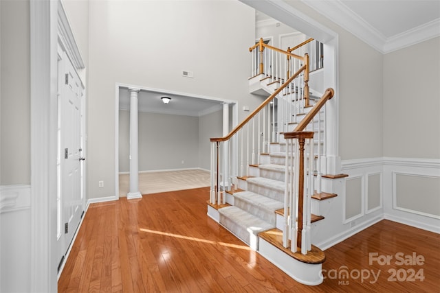 stairway with hardwood / wood-style flooring, ornate columns, and crown molding