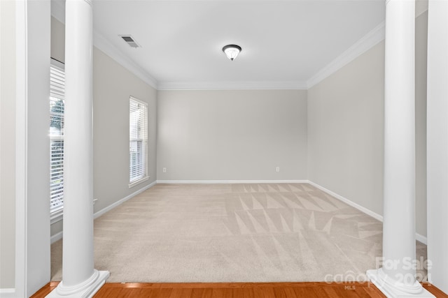 carpeted spare room featuring decorative columns and crown molding