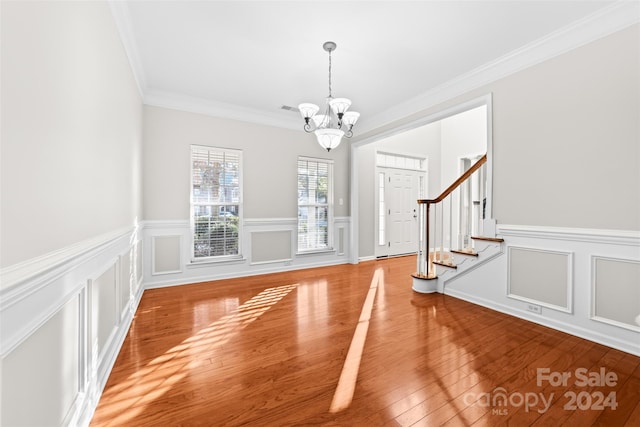 foyer featuring wood-type flooring, an inviting chandelier, and ornamental molding